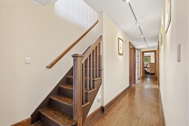 stairs featuring wood-type flooring and track lighting