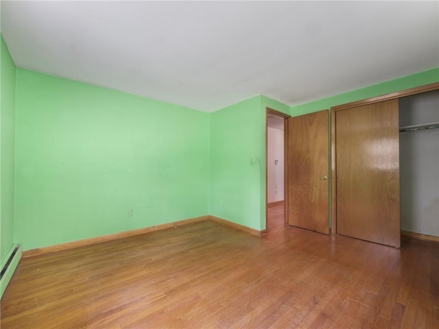 unfurnished bedroom with a closet, a baseboard radiator, and light wood-type flooring