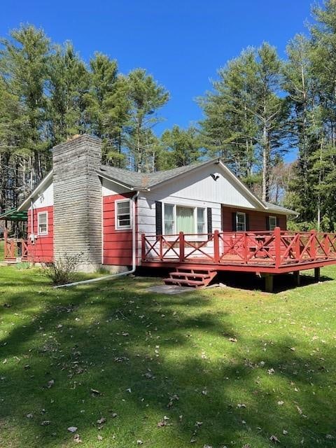 back of property with a yard and a wooden deck