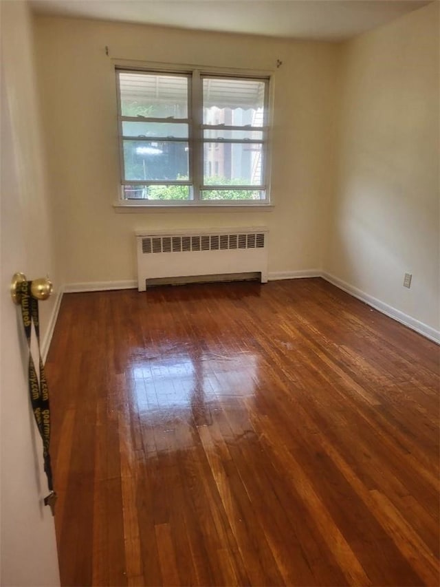 unfurnished room featuring radiator and dark hardwood / wood-style flooring