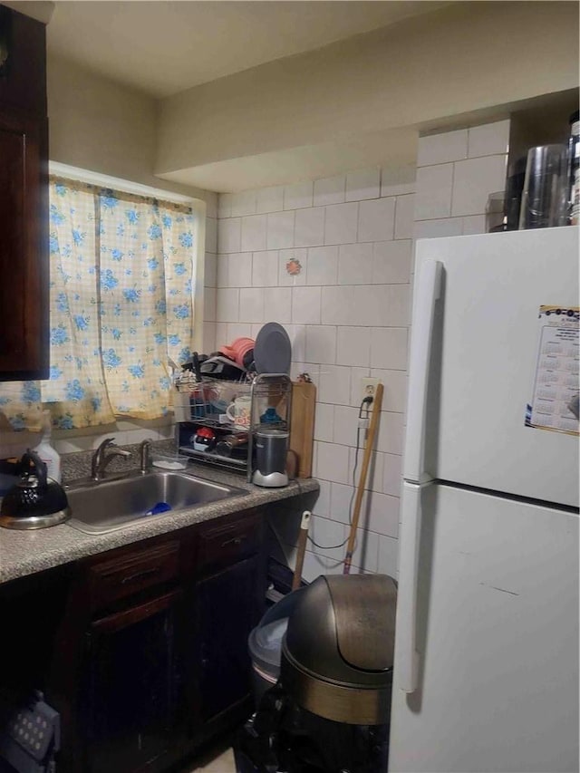 kitchen featuring dark brown cabinets, white refrigerator, sink, and tasteful backsplash