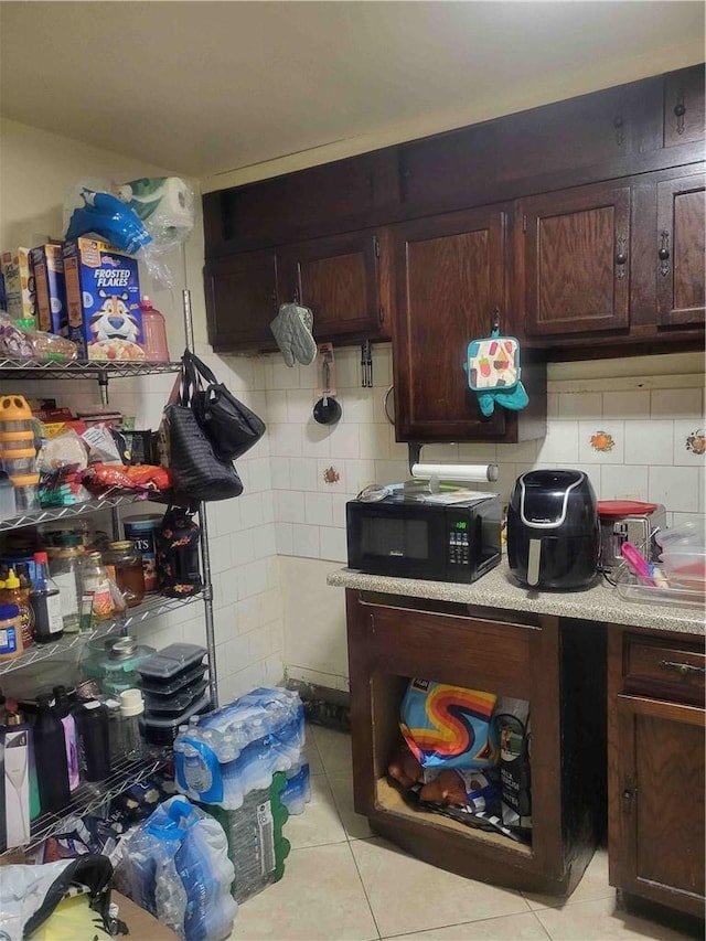 kitchen featuring decorative backsplash, light tile patterned floors, and dark brown cabinets