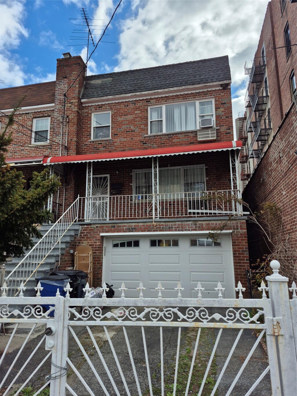 740 Nereid Ave, Bronx, NY 10466 - view of front of property featuring an attached garage, cooling unit, a fenced front yard, and brick siding