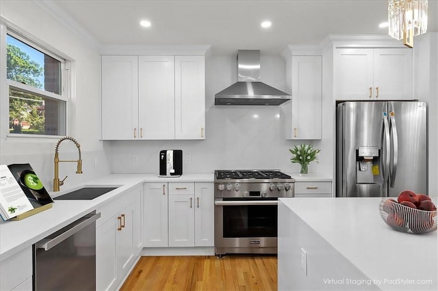 kitchen featuring white cabinets, wall chimney exhaust hood, and appliances with stainless steel finishes