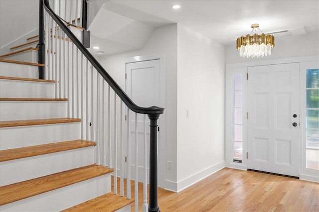 entryway with light hardwood / wood-style floors and a notable chandelier