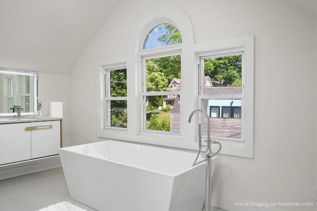 bathroom with tile patterned floors, plenty of natural light, vanity, and vaulted ceiling