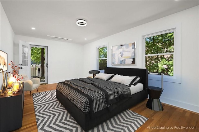 bedroom with hardwood / wood-style flooring, access to exterior, and multiple windows