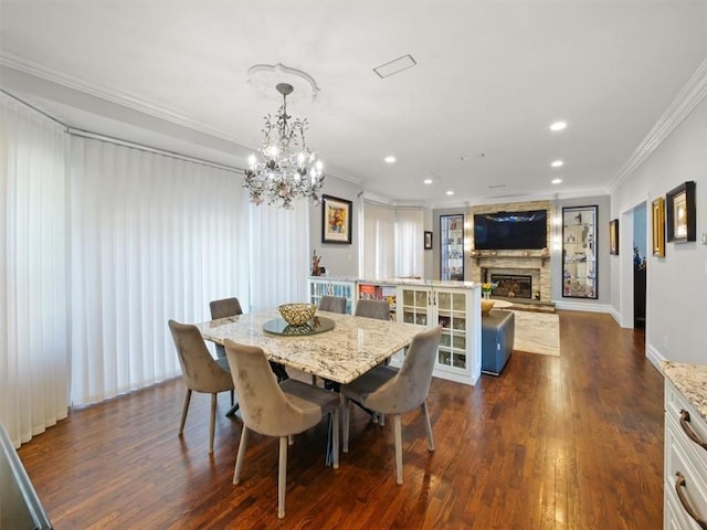 dining area featuring a fireplace, dark hardwood / wood-style floors, crown molding, and a notable chandelier