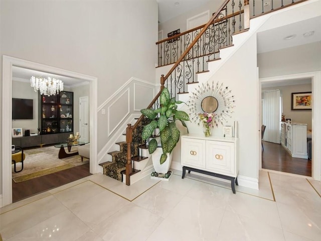 staircase featuring wood-type flooring, a notable chandelier, and ornamental molding