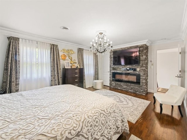 bedroom with a fireplace, ornamental molding, a notable chandelier, and hardwood / wood-style flooring