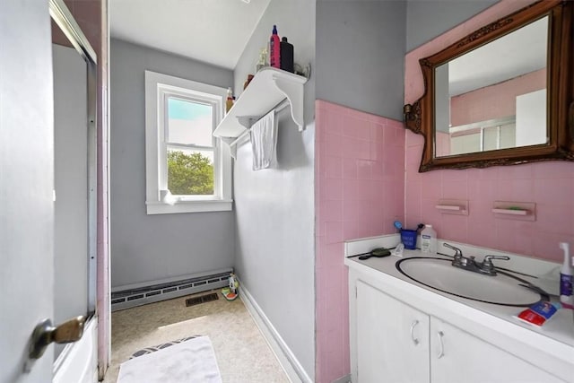 bathroom with a shower, vanity, baseboard heating, and tile walls