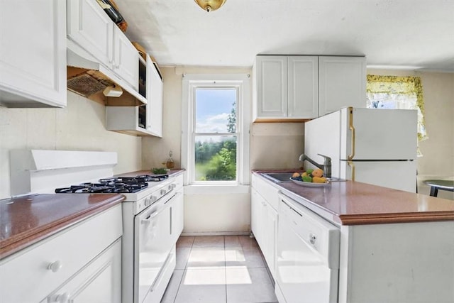 kitchen with light tile patterned flooring, white appliances, white cabinetry, and sink