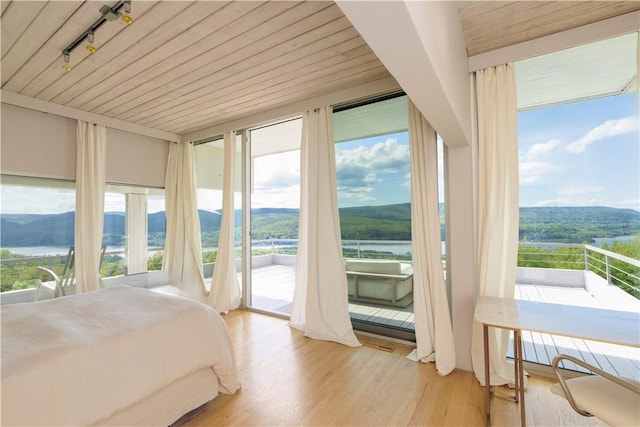 bedroom featuring access to exterior, light hardwood / wood-style flooring, multiple windows, and wood ceiling