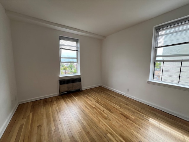 unfurnished room featuring radiator heating unit and light hardwood / wood-style floors