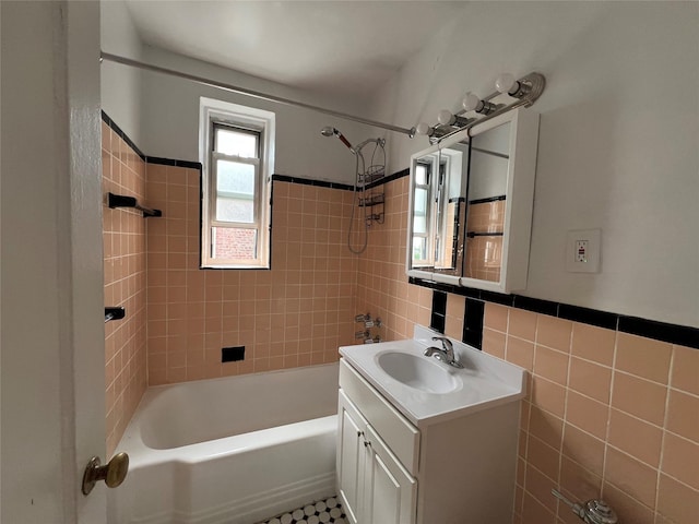 bathroom featuring tiled shower / bath combo, vanity, and tile walls