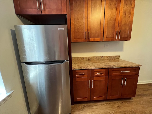 kitchen featuring light stone counters, stainless steel refrigerator, and light hardwood / wood-style flooring