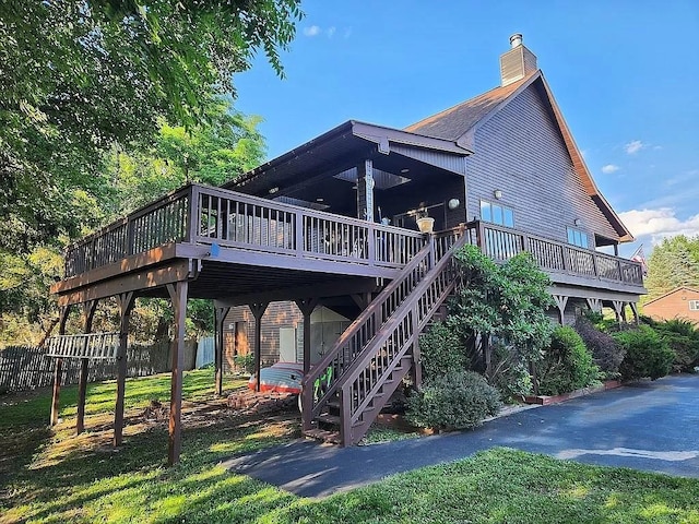 rear view of house featuring a lawn and a wooden deck