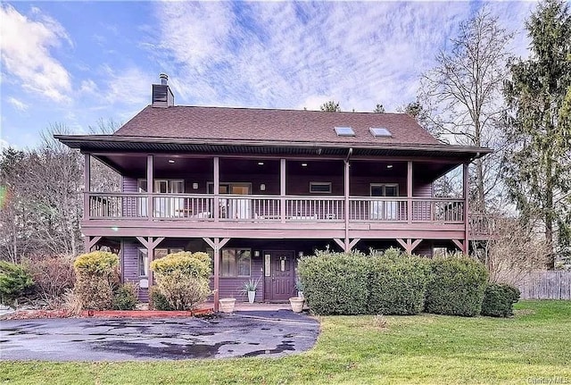 rear view of property featuring a lawn and a wooden deck