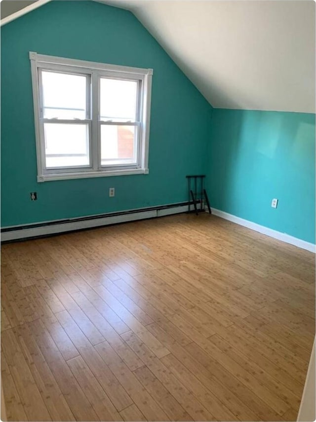 bonus room with light hardwood / wood-style flooring, lofted ceiling, and a baseboard heating unit