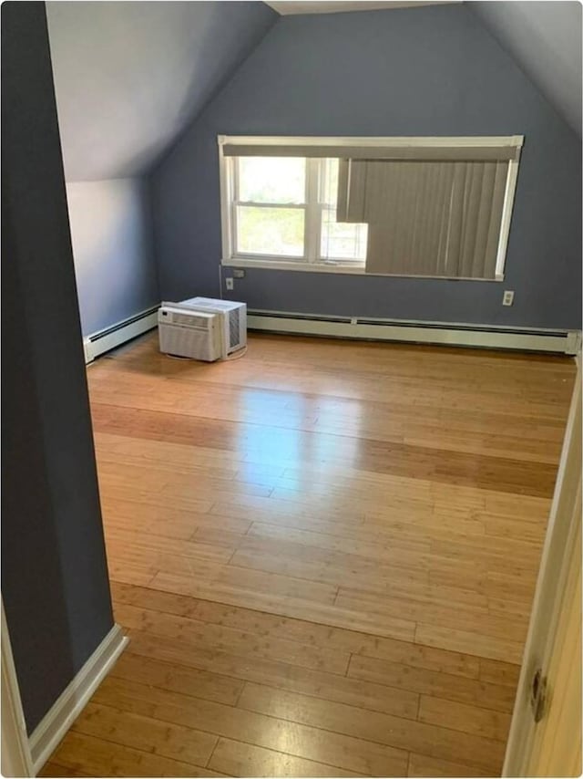 additional living space featuring light hardwood / wood-style flooring, a baseboard radiator, and vaulted ceiling