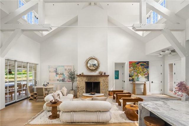 living room featuring a high end fireplace, light wood-type flooring, high vaulted ceiling, and ceiling fan