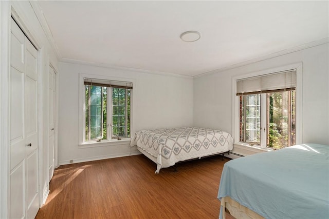 bedroom with multiple windows, crown molding, a closet, and hardwood / wood-style flooring