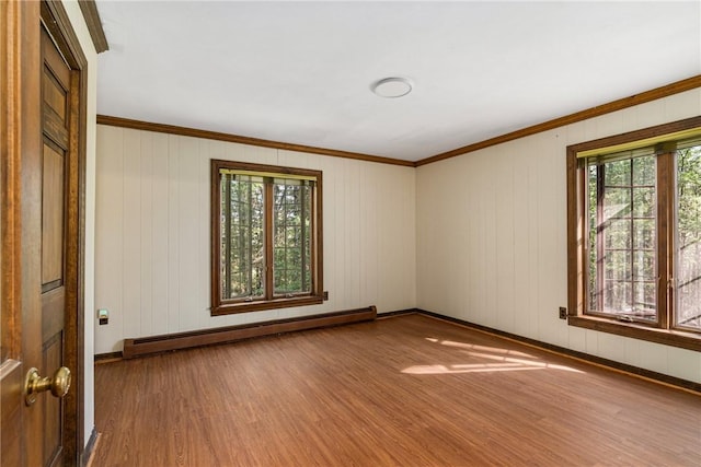 spare room with wooden walls, ornamental molding, a baseboard radiator, and hardwood / wood-style flooring