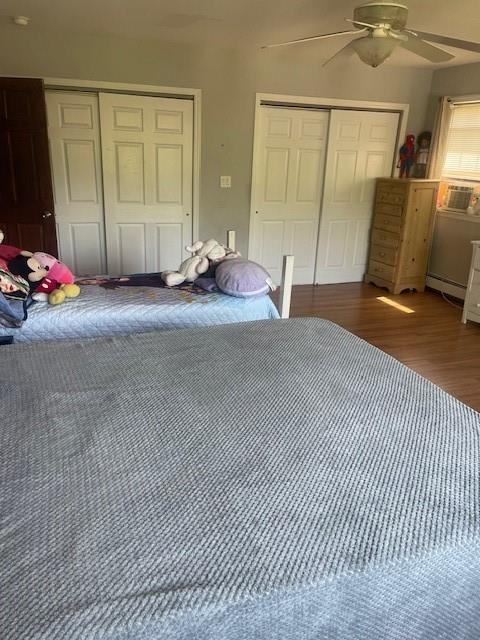 unfurnished bedroom featuring ceiling fan, dark hardwood / wood-style flooring, and a baseboard radiator