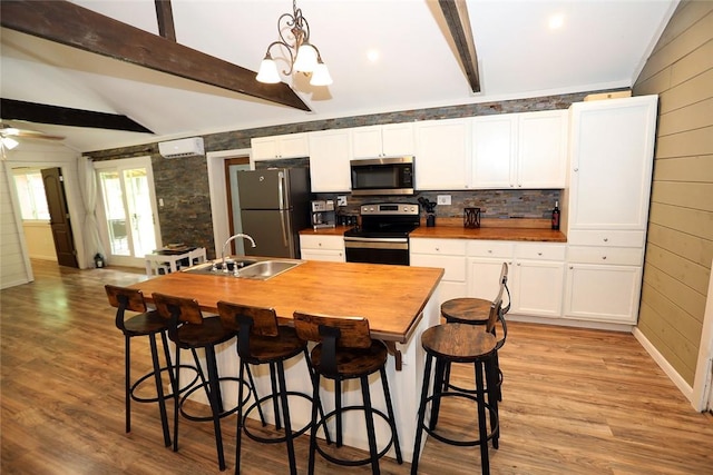 kitchen featuring hanging light fixtures, sink, light hardwood / wood-style flooring, appliances with stainless steel finishes, and butcher block countertops