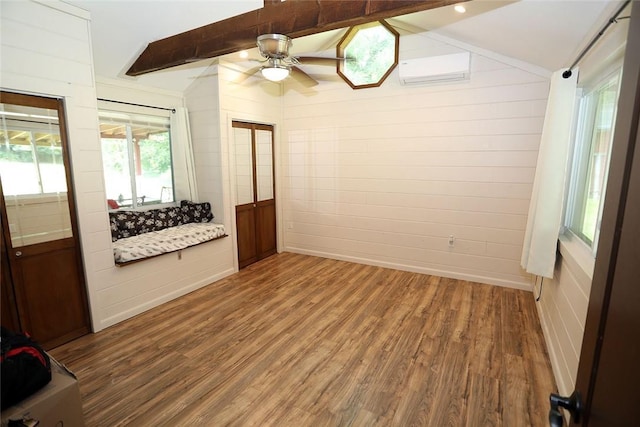 unfurnished room featuring hardwood / wood-style floors, vaulted ceiling with beams, ceiling fan, and a wall mounted air conditioner