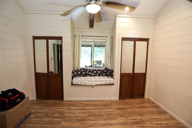 hall featuring hardwood / wood-style flooring, wood walls, and lofted ceiling