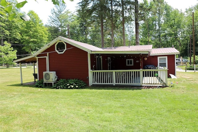 rear view of property with ac unit and a yard