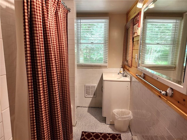 bathroom featuring tile patterned flooring, vanity, tile walls, and walk in shower