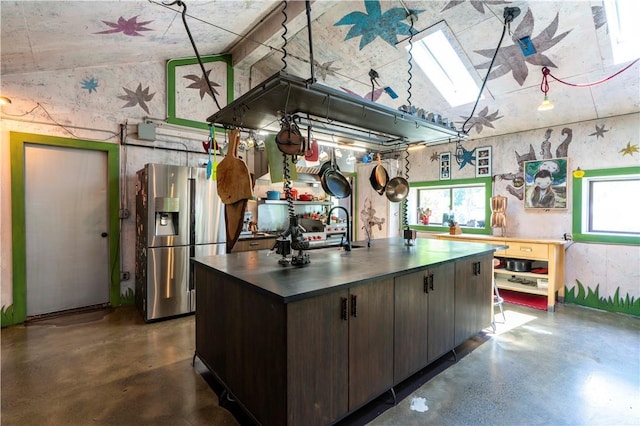 kitchen with sink, stainless steel fridge, dark brown cabinetry, and an island with sink