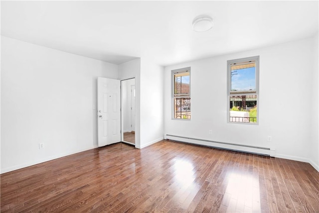 empty room featuring a baseboard radiator and hardwood / wood-style flooring