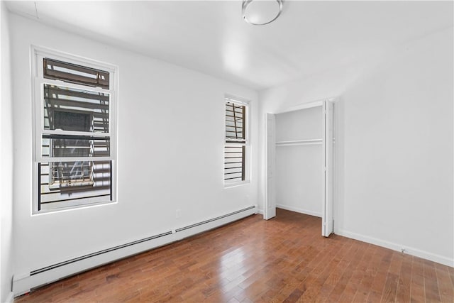 unfurnished bedroom featuring hardwood / wood-style floors and baseboard heating