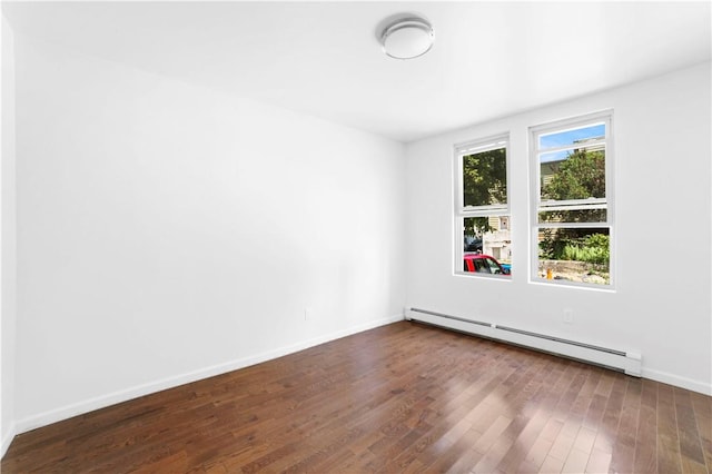 spare room with dark hardwood / wood-style flooring and a baseboard heating unit