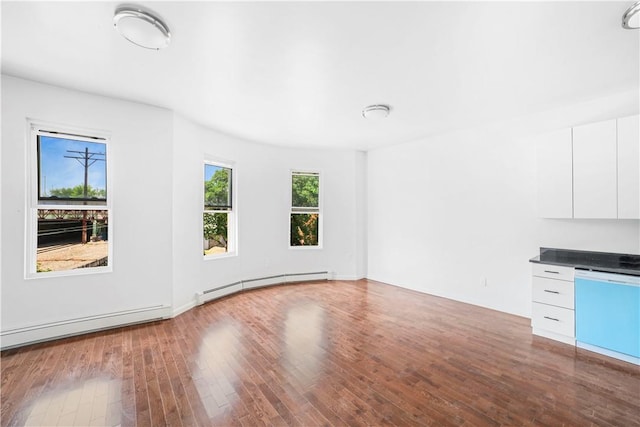 unfurnished living room with hardwood / wood-style flooring and a baseboard heating unit