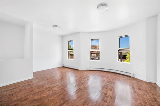 spare room featuring hardwood / wood-style flooring and a baseboard heating unit