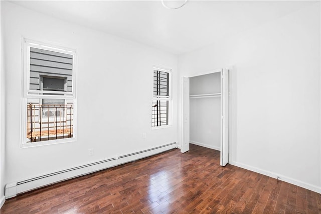 unfurnished bedroom with baseboard heating and dark wood-type flooring