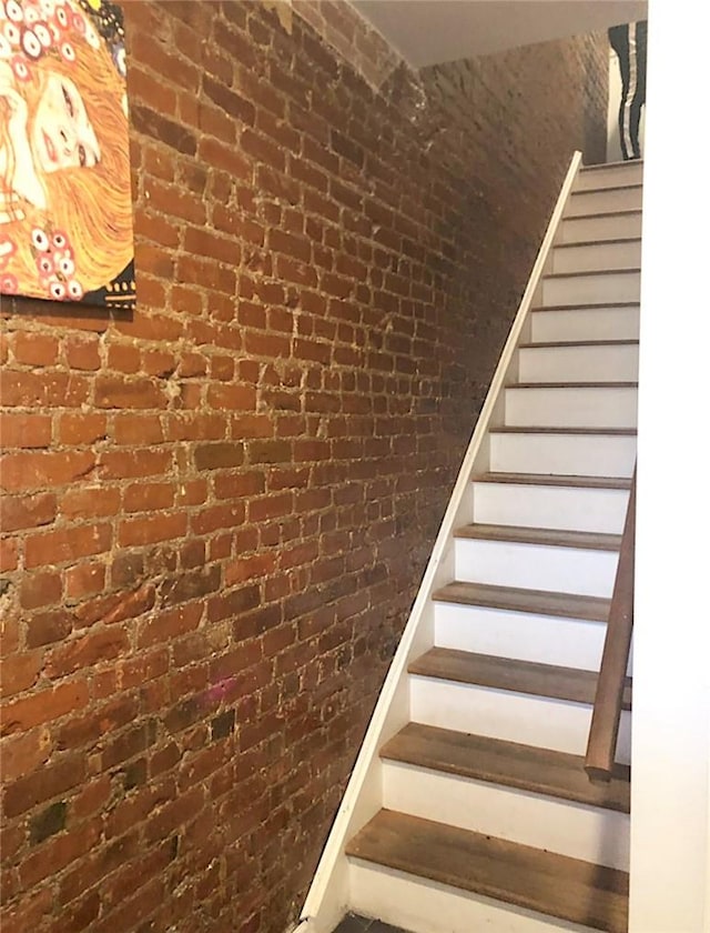 staircase featuring brick wall