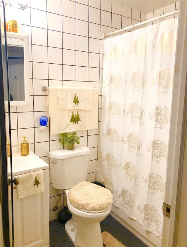 bathroom with toilet, tile patterned floors, tile walls, and curtained shower