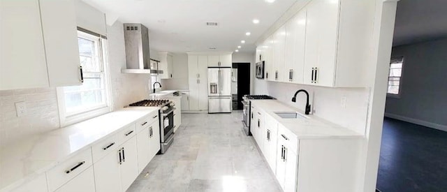 kitchen with white cabinetry, sink, wall chimney exhaust hood, tasteful backsplash, and appliances with stainless steel finishes