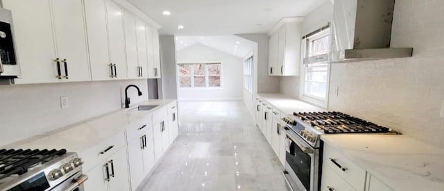 kitchen with white cabinetry, stainless steel gas stove, extractor fan, and plenty of natural light