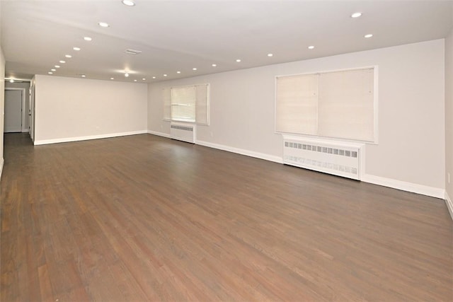 unfurnished room featuring dark hardwood / wood-style floors and radiator heating unit