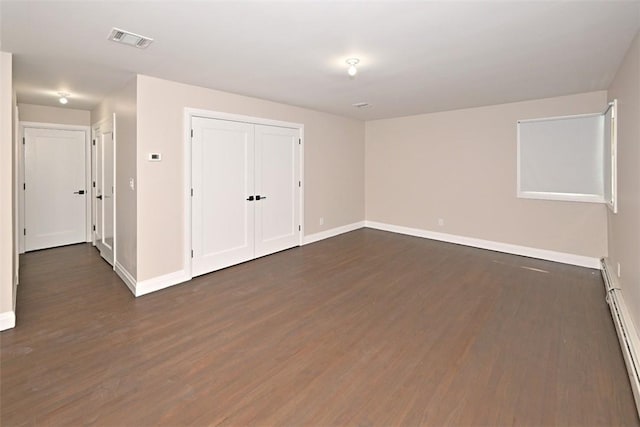 unfurnished room featuring dark hardwood / wood-style flooring and a baseboard radiator