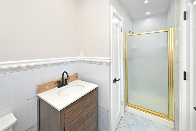 bathroom with vanity, tile walls, tile patterned flooring, toilet, and a shower with shower door