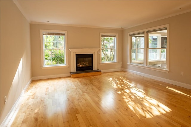 unfurnished living room featuring a wealth of natural light, light hardwood / wood-style floors, and ornamental molding