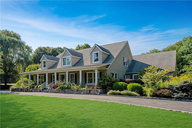 new england style home featuring a porch and a front lawn