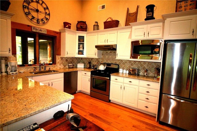 kitchen with white cabinets, sink, light stone countertops, and stainless steel appliances